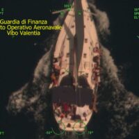 Immagine di una barca in mare notturno, con luci verdi e testo italiano in alto a sinistra.