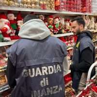 Due vigilantes della Guardia di Finanza osservano scaffali di abbigliamento natalizio in un negozio, SR personaggi in azione tra giocattoli.