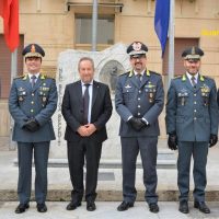 Quattro ufficiali militari in uniforme e un uomo in abito parlano davanti a una targa commemorativa su una scalinata