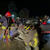 Intervento di soccorso notturno: vigili del fuoco su un incidente stradale con veicoli danneggiati e soccorritori al lavoro.