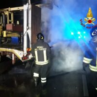 Soccorritori al lavoro durante l’intervento, fumo e luci blu sullo sfondo, veicolo di emergenza e personale in divisa riflettente.