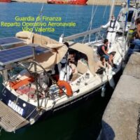Barche ormeggiate al porto con personale operante, pullman e molo, in italiano: Guardia di Finanza Reparto Operativo Aeronavale Wind Valentina.