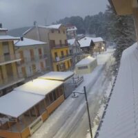 Veduta di una strada invernale di montagna con edifici colorati, neve sui tetti e le strade, atmosfera tranquilla e fredda.