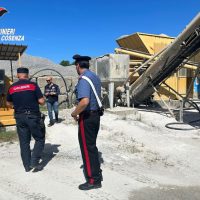 operai al lavoro in cantiere con gru e strutture in cemento sotto cielo azzurro, su strada polverosa e abbigliamento da sicurezza