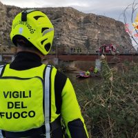 Vigili del fuoco in alta visibilità gialla di fronte a un paesaggio roccioso e attività di salvataggio vicino all’acqua