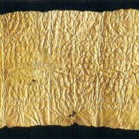 Foglio d'oro sfumato con texture scanalata su sfondo scuro, riflessi metallici e pieghe irregolari.