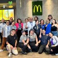 Gruppo di dipendenti McDonald's posati per foto di gruppo inside, in abiti casual, sorridenti e ben allineati.