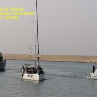 Barca a vela con passeggeri in navigazione nel porto di Valencia, giorno sereno e mare tranquillo.