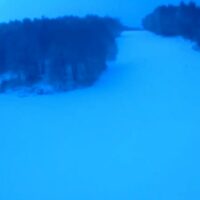 Scorcio di fiume ghiacciato tra alberi, tonalità blu intenso e riflessi ghiacciati sulla superficie.
