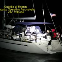 Lunetta di una barca al largo di notte, personale in uniforme illuminato da luci, attività di soccorso operativa