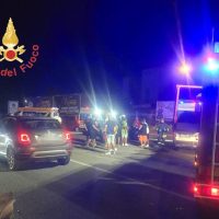 Soccorsi notturni: incendio o incidente su strada, mezzi dei vigili del fuoco e auto in ripiegamento, personale sul posto.