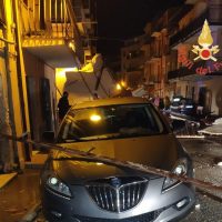 Auto incidentata davanti a un edificio, luci notturne, outcome di cantiere e decorazioni natalizie sullo sfondo.