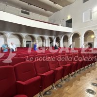 Sala allestita con palchi e sedie rosse, arcate e balcone superiore, ambiente luminoso e professionale.