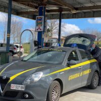 Auto della guardia di finanza al distributore, veicolo grigio con strisce gialle, marchio GDF e allestimento di servizio.