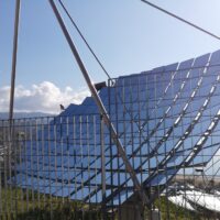 Paesaggio urbano solare con pannelli fotovoltaici su tetto inclinato, strutture metalliche e cielo sereno.