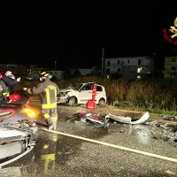 Incidente stradale notturno: veicoli danneggiati, vigili del fuoco e soccorritori presenti sulla carreggiata.