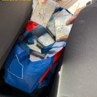 Rifiuti in un bidone: sacchi di plastica Blu e imballaggi metallici, pezzi vari tra carta e pellicole, nascosti tra contenitori e oggetti.