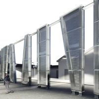 Pannelli metallici in vetroresina formano una facciata laterale di edificio moderno, con una persona al passaggio.