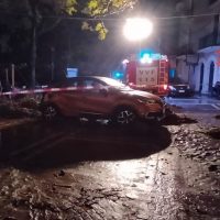 Auto urta al miio di strada bagnata, lampeggianti di emergency illuminano la scena notturna.