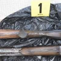 Bottiglie di vetro rotti e segni di analisi forense su superficie nera, etichetta gialla con numero 1 visibile.