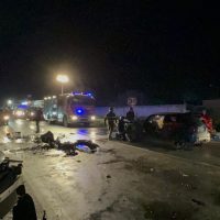 Incidente stradale notturno: veicoli danneggiati, ambulanze in azione e soccorritori sul luogo.