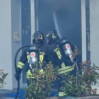 Due vigili del fuoco in attrezzatura completa entrano in una finestra aperta di un edificio, con luci e tute riflettenti, durante un intervento.