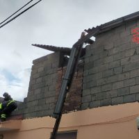 Operai al lavoro su un muro di blocchi, perdita o cedimento della parete con travi metalliche appoggiate e ponteggio parziale.