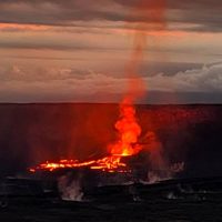 Eruttante vulcano con lava incandescente che scorre, fumo e cielo al tramonto sullo sfondo.