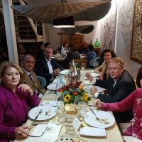 Gruppo di persone a tavola durante una cena elegante, servizio impeccabile e atmosfera conviviale in un ristorante accogliente.