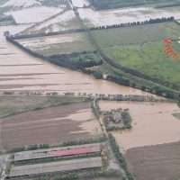 Veduta aerea di campi agricoli divisi da canali e strade, con aree verdeggianti e un paesaggio rurale sereno
