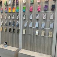 Collezione di piccoli campioni di tessuti o materiali colorati, appesi a una griglia metallica su due pannelli, con tag descrittivi.
