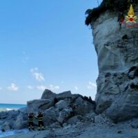 .SC01 Orizzonte roccioso sul mare, spiaggia sassosa e cielo azzurro: due figure in silenzio vicino alle rocce bianche.