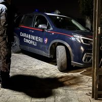 Auto dei Carabinieri Genova, veicolo blu con scritte e lampeggianti, all’ingresso di un edificio al chiaro di notte