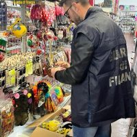 Persona in giacca scura assortisce accessori colorati in un negozio di altri gadgets, con una vetrina piena di bijoux frizzanti sullo sfondo.