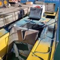 Anch’io: barche da lavoro sul molo, sedie pieghevoli e borsa, hardware nautico e attrezzature all’aperto, colori vividi sul pontile.