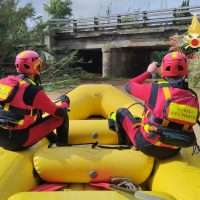 Due esperti in da diving equipaggiati su una zattera gialla, pronti a scendere verso il fiume sotto un ponte.