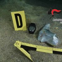 Scena del sopralluogo: marker D, maschera, guanti e strumenti da rilevamento su pavimento. Logo Carabinieri in alto a destra.