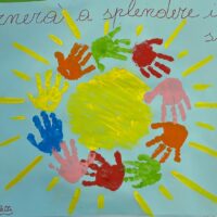 Disegno infantile con una mano gigante gialla al centro e mani colorate attorno, raggi luminosi su sfondo azzurro.