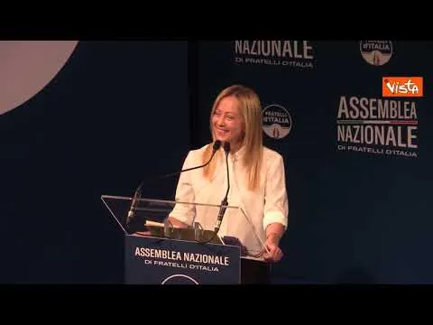 La gag di Meloni all'Assemblea di FdI, alza il braccio destro, poi ci ripensa